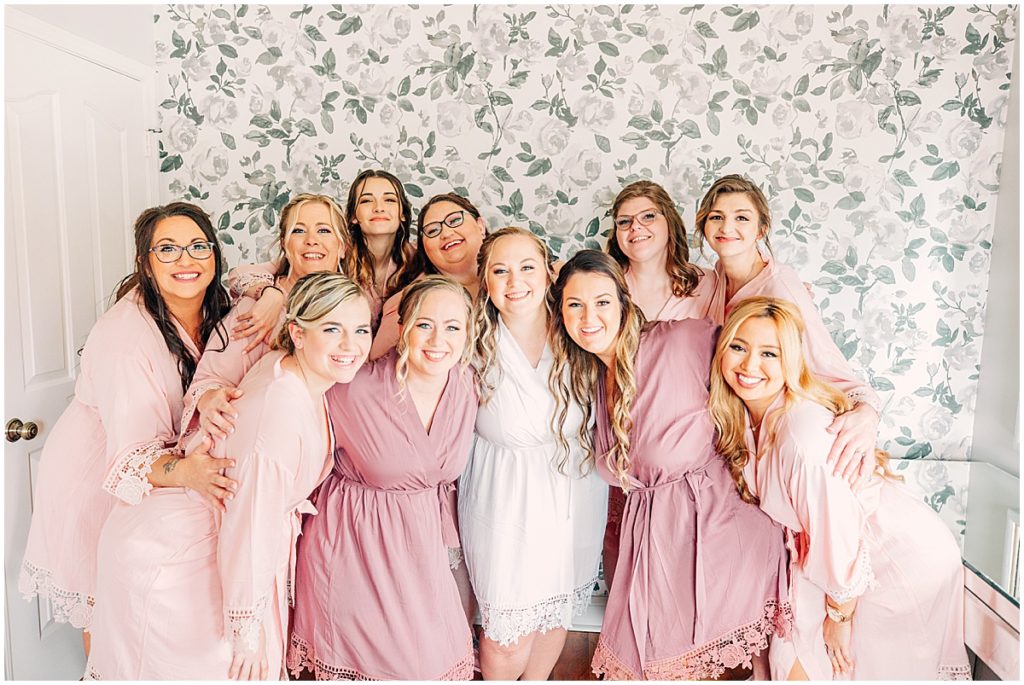 Bride with bridesmaids in front of floral wall