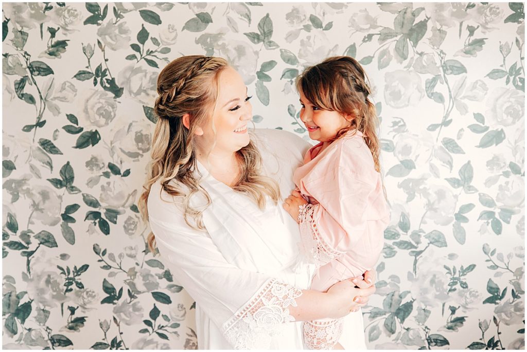 Bride with young girl in front of floral wall