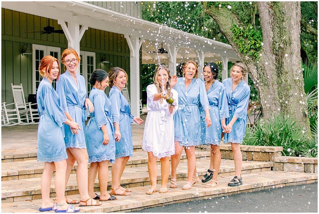 Bride popping champagne with bridesmaids 