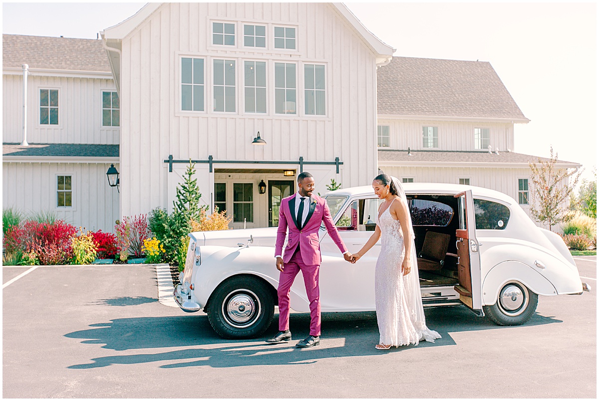 White wedding gettaway car with groom in pink suite and bride in white dress. By Nikki Golden Photography, Destination wedding photographer