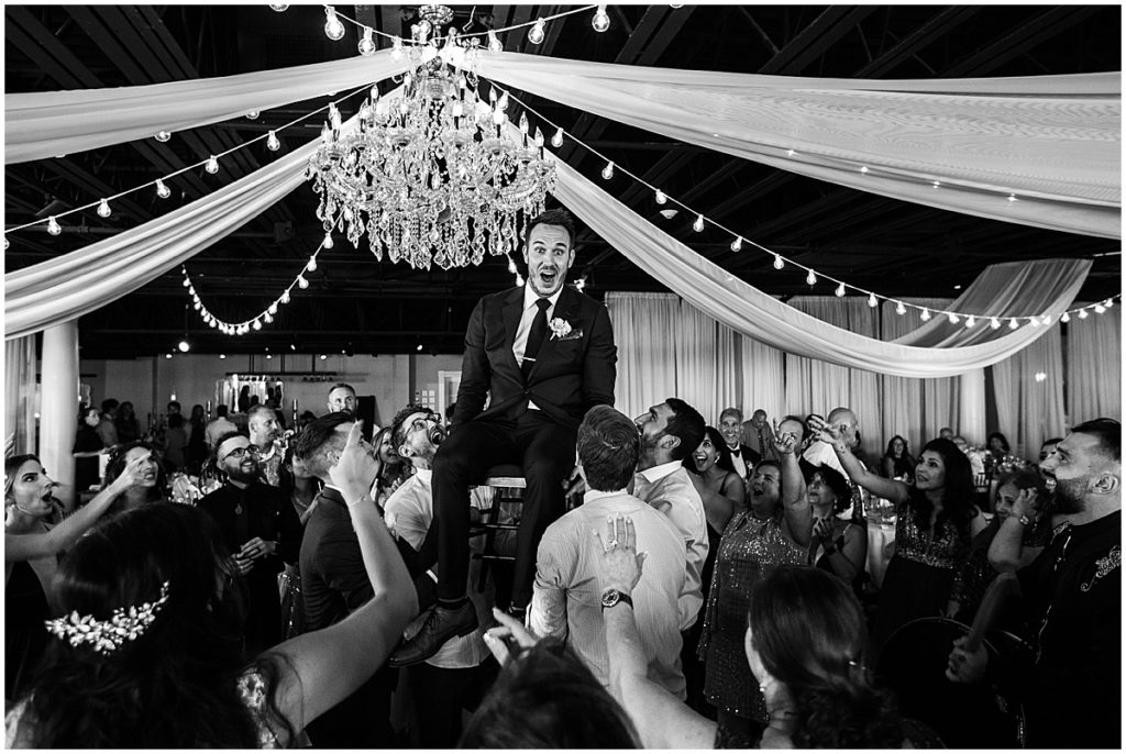 Groom being lifted on a chair at a wedding reception | Nikki Golden Photography