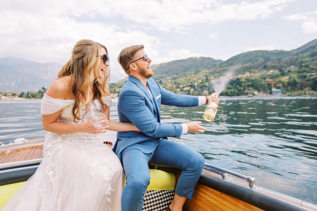 Bride and groom popping champagne on a boat in lake como italy