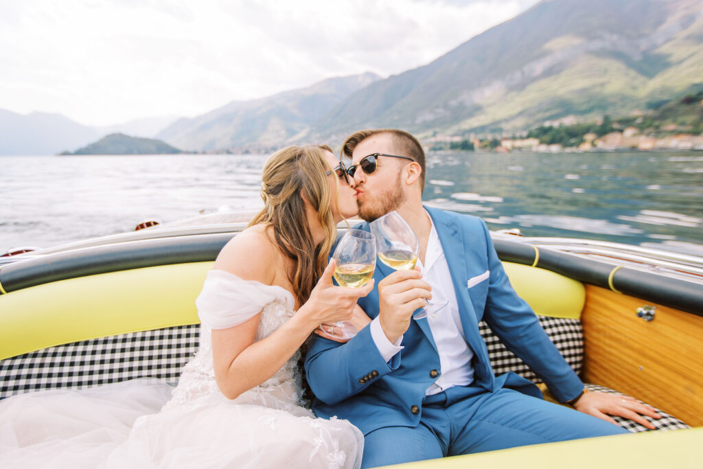 Bride and groom toasting champagne and kissing on a boat in lake como italy