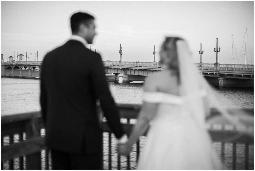 black and white photo of a bride and groom on a dock in front of a long bride in St Augustine FL