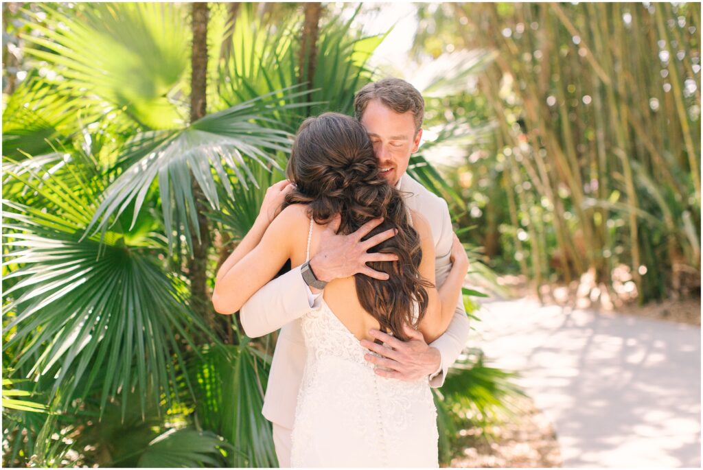 bride and groom hugging in front of a tropical greenery background