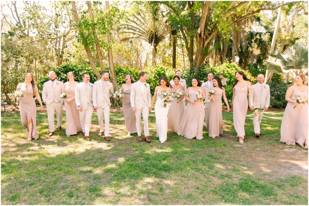 bridal party walking all together in front of a tropical greenery background