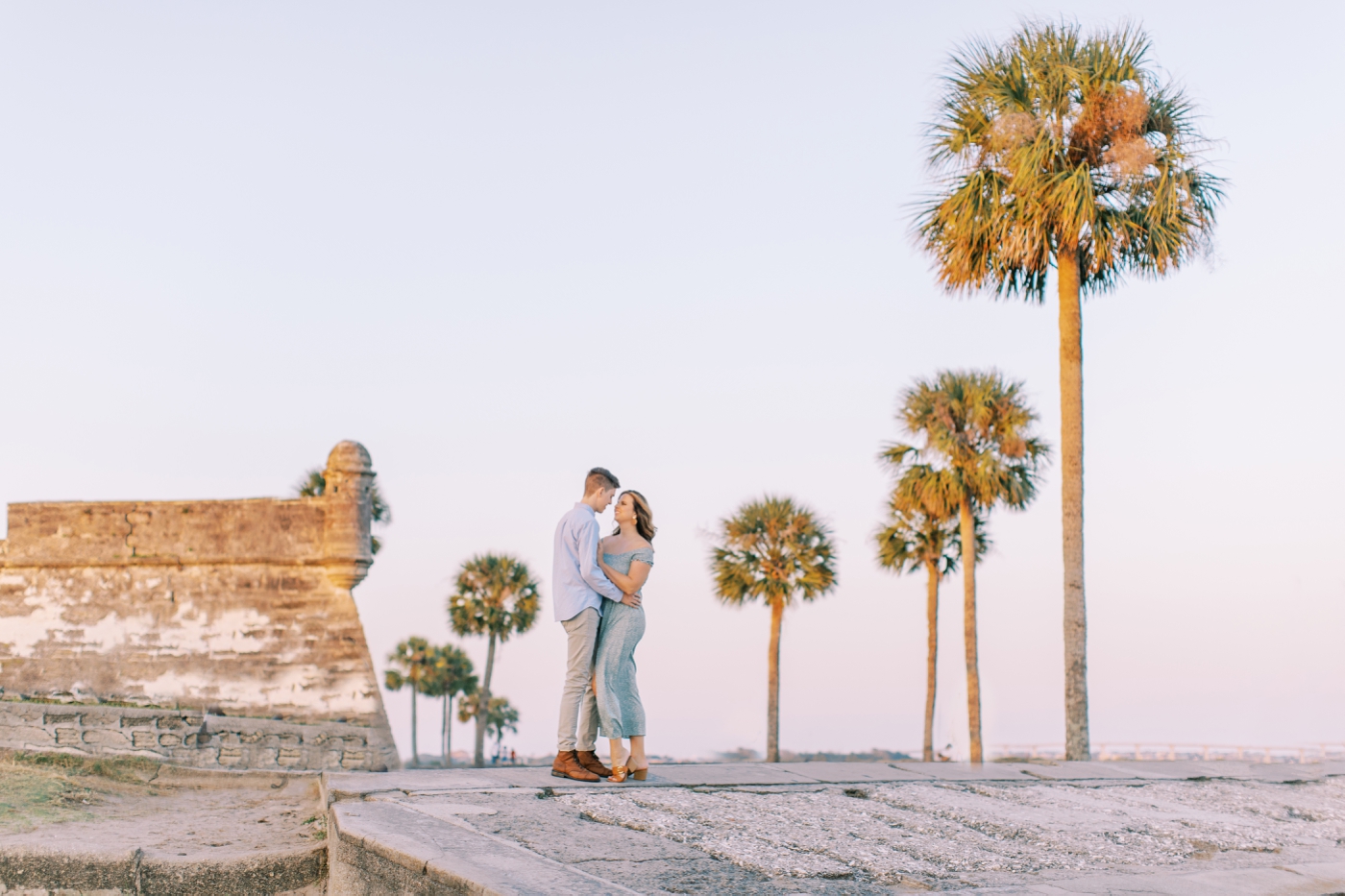 Sunset proposal at Castillo de San Marcos with the bay in the background and palm trees