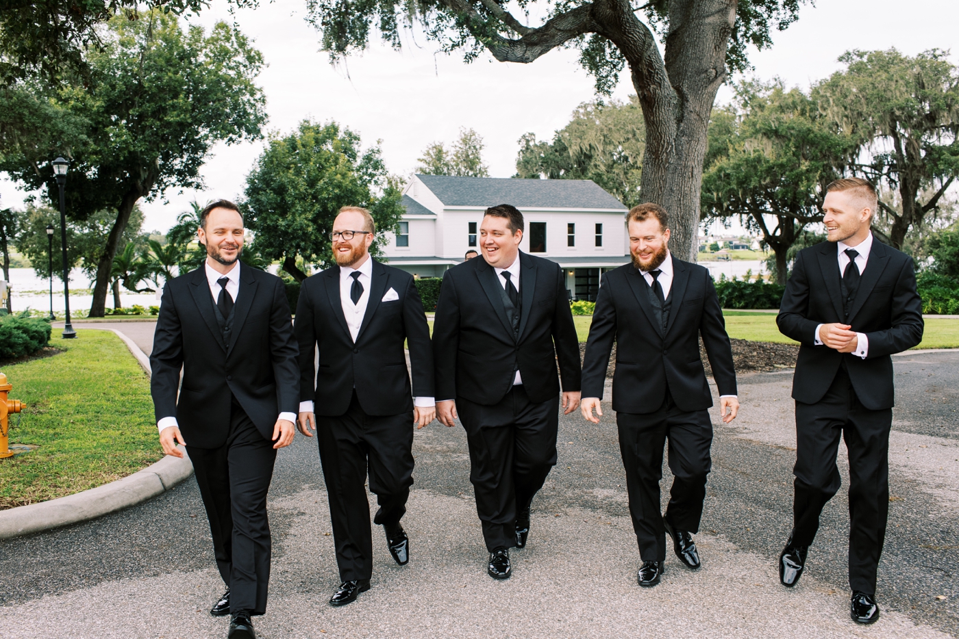 Groom and groomsmen walking down paved road 