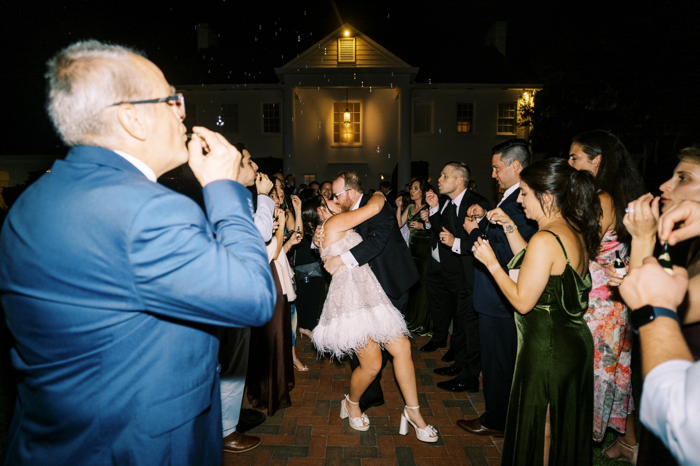 Bride and groom kissing during grand exit with bubbles